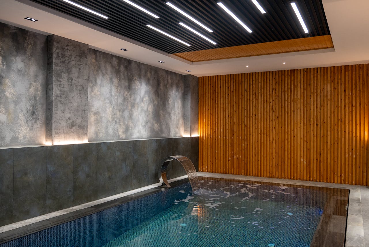 Relaxing indoor pool area featuring modern lighting and elegant wood paneling design.